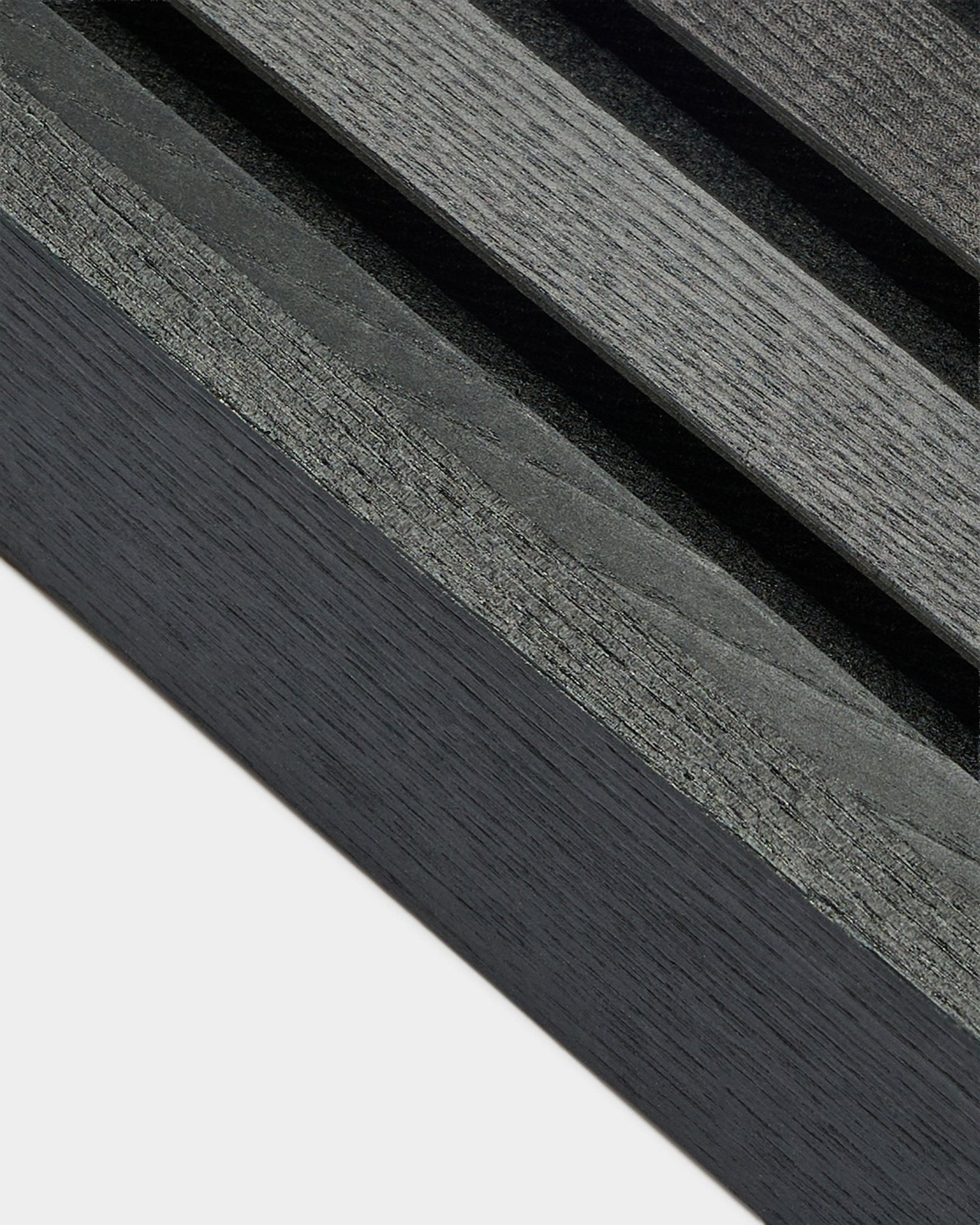 Close-up of WoodUpp Akupanel End lamella in Black Ash (6.7cm), showing dark gray wood grain on a light base, designed for Nordic acoustic panel installations.