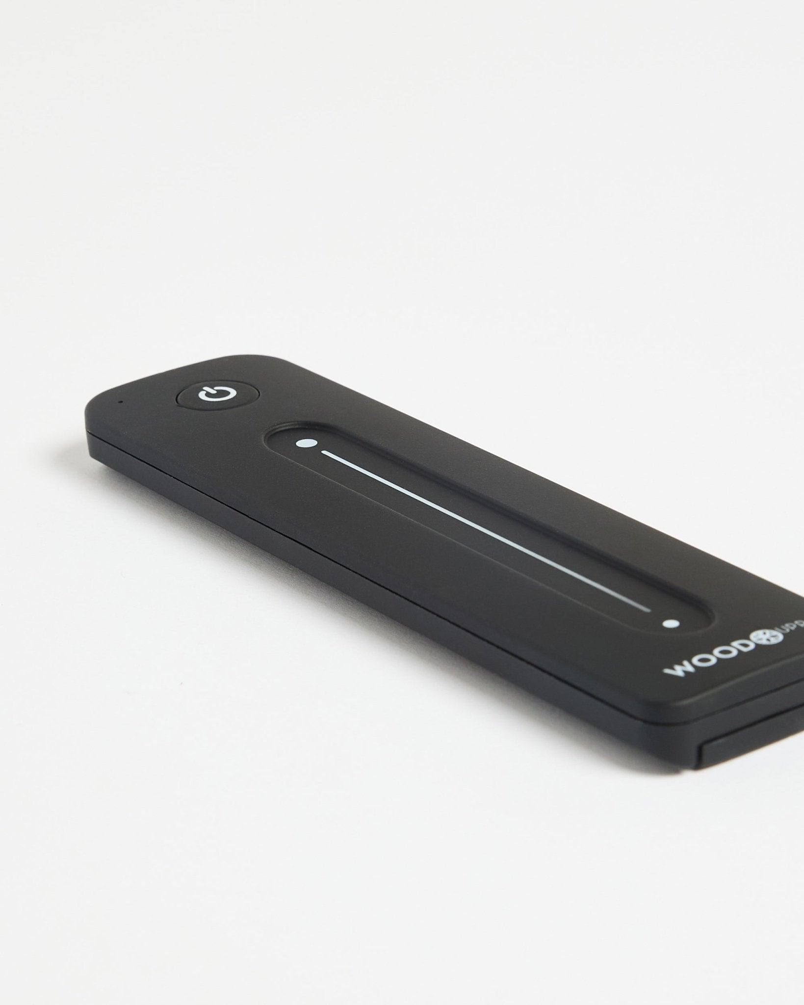WoodUpp Lumi Remote for LED striplights in black, with power button, Philips Hue compatible, displayed on a white surface.