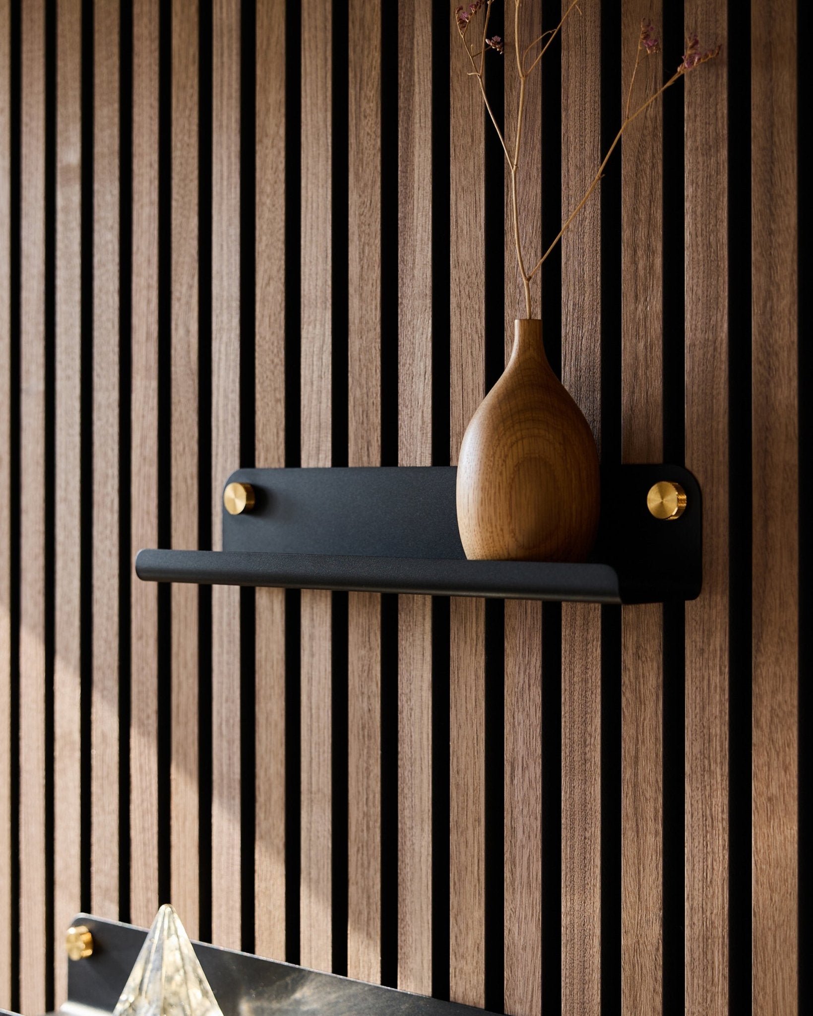 A wooden vase with dried branches on a black WoodUpp Norr Narrow shelf (35.9 cm), set against a vertical Nordic-style acoustic slatwall panel.