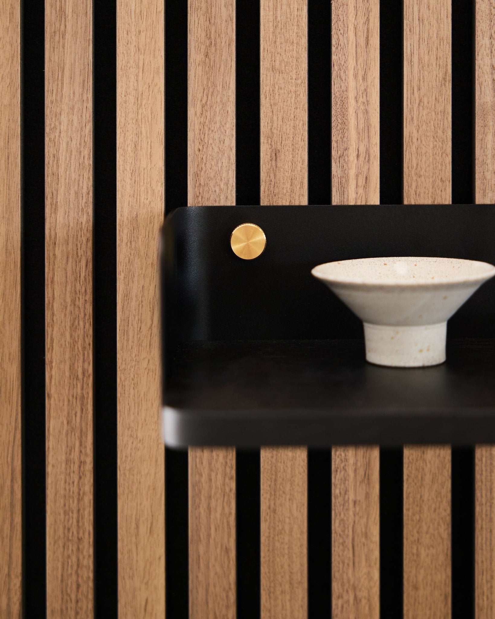 Ceramic bowl placed on Linn Bookshelf by WoodUpp, 39.9 cm in black oak with vertical black slats and a brass accent, reflecting Nordic minimalist design.