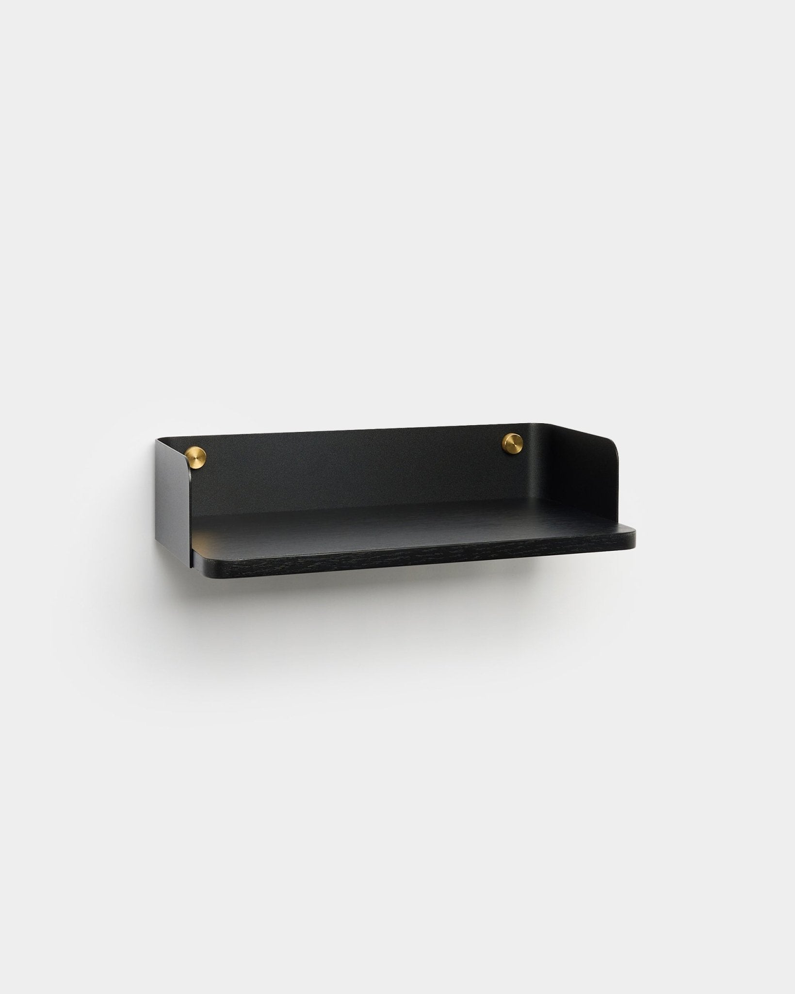 Linn Bookshelf by WoodUpp, in a minimalist black finish with brass mounting screws, is mounted on a light gray wall, complementing Nordic interior design.