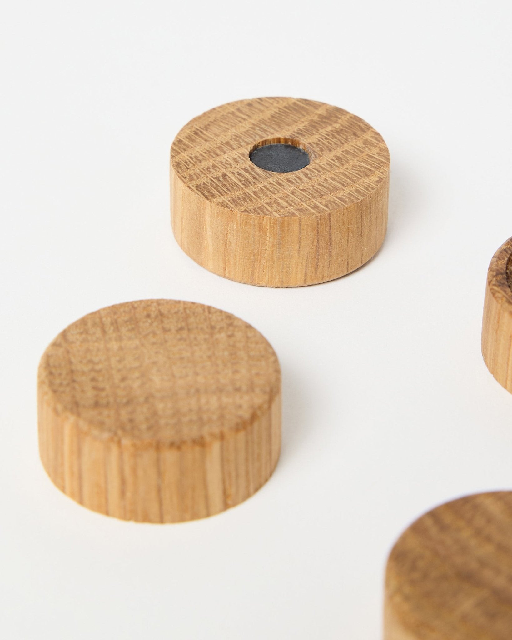Set of four natural oak magnets by WoodUpp, designed for use with Akupanel acoustic wood panels, one featuring a central neodymium magnet for extra grip, displayed on white.