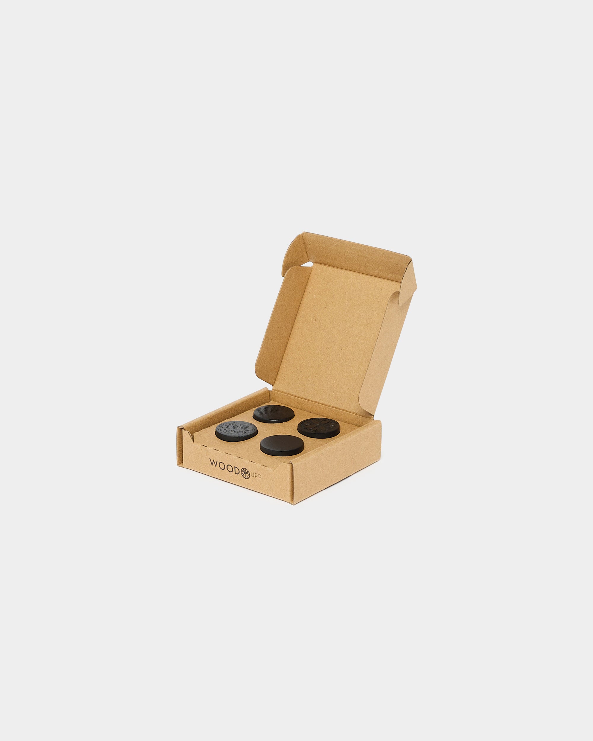Open brown cardboard box containing four round black wheels arranged in a square formation, placed on a plain white background.