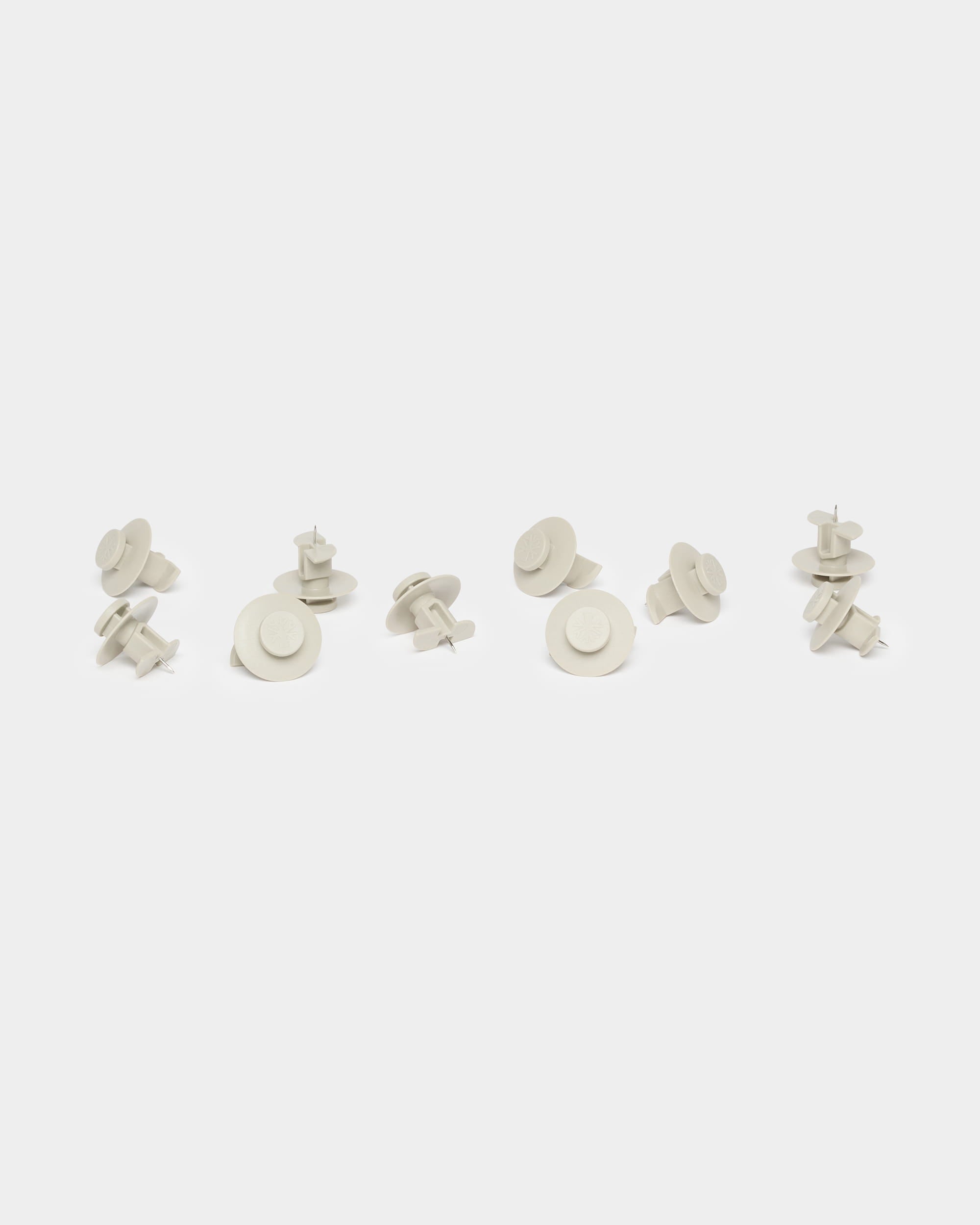 Ten beige Dupps push pins by WoodUpp, used as Akupanel accessories, are loosely grouped on a plain white background.