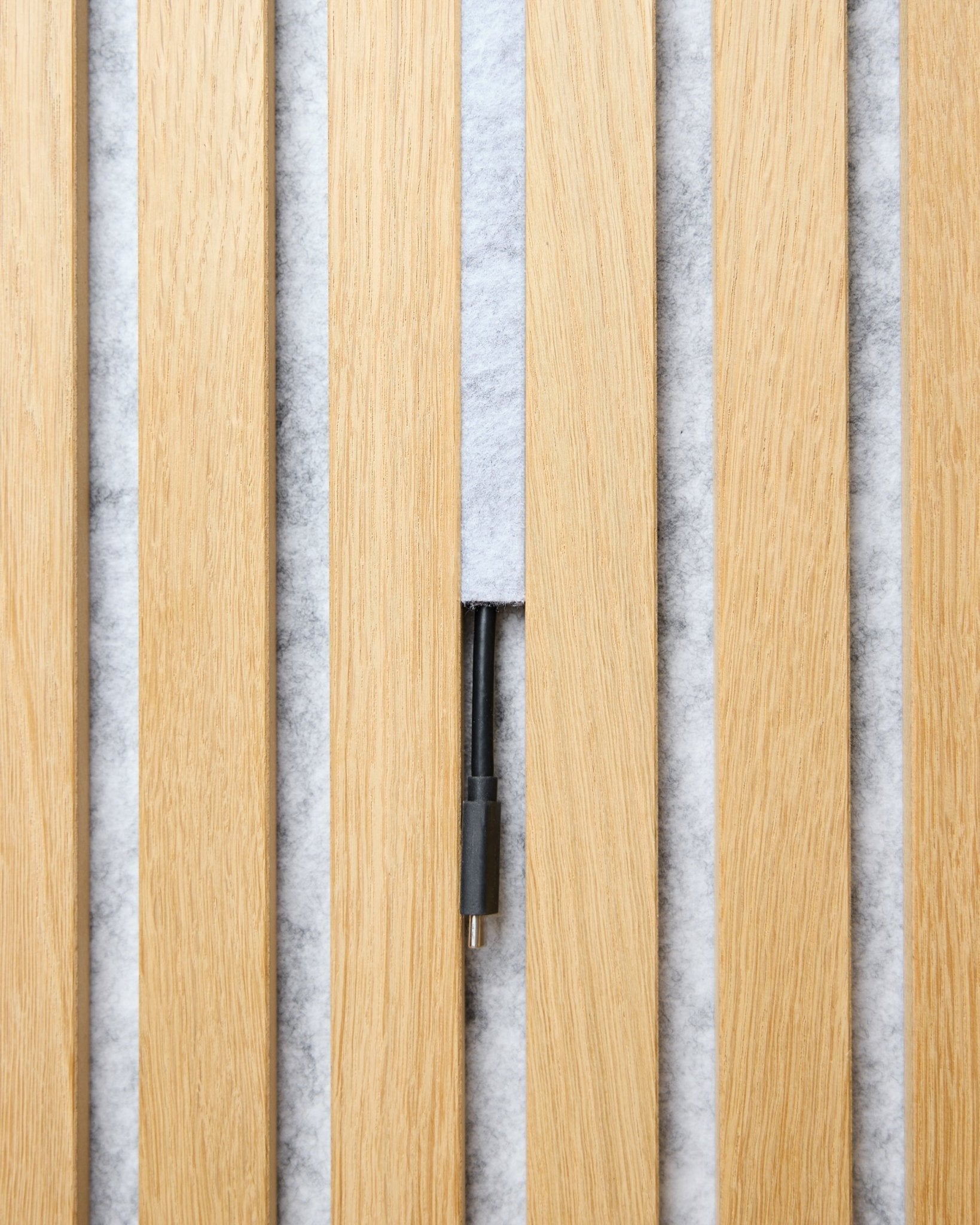 Dupps Pop-on Cable Cover set (grey, 3 pcs) by WoodUpp organizes cables between light wood Akupanel slats on a white textured background.
