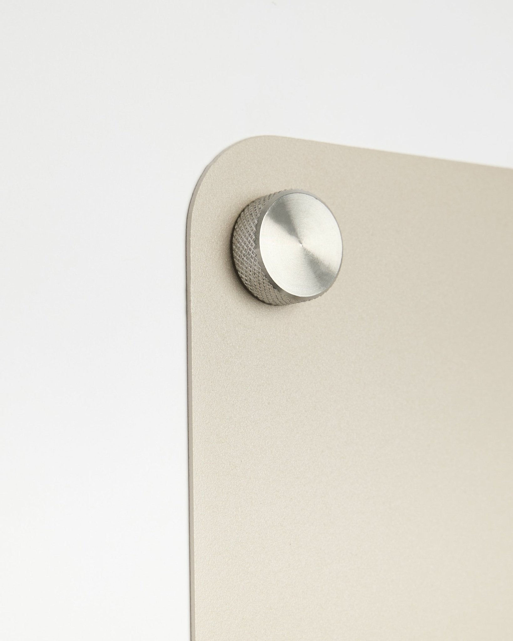 Close-up of a round metal knob accessory attached to the large beige Norr Magnetic Board by WoodUpp, with frosted glass detail on a white background.