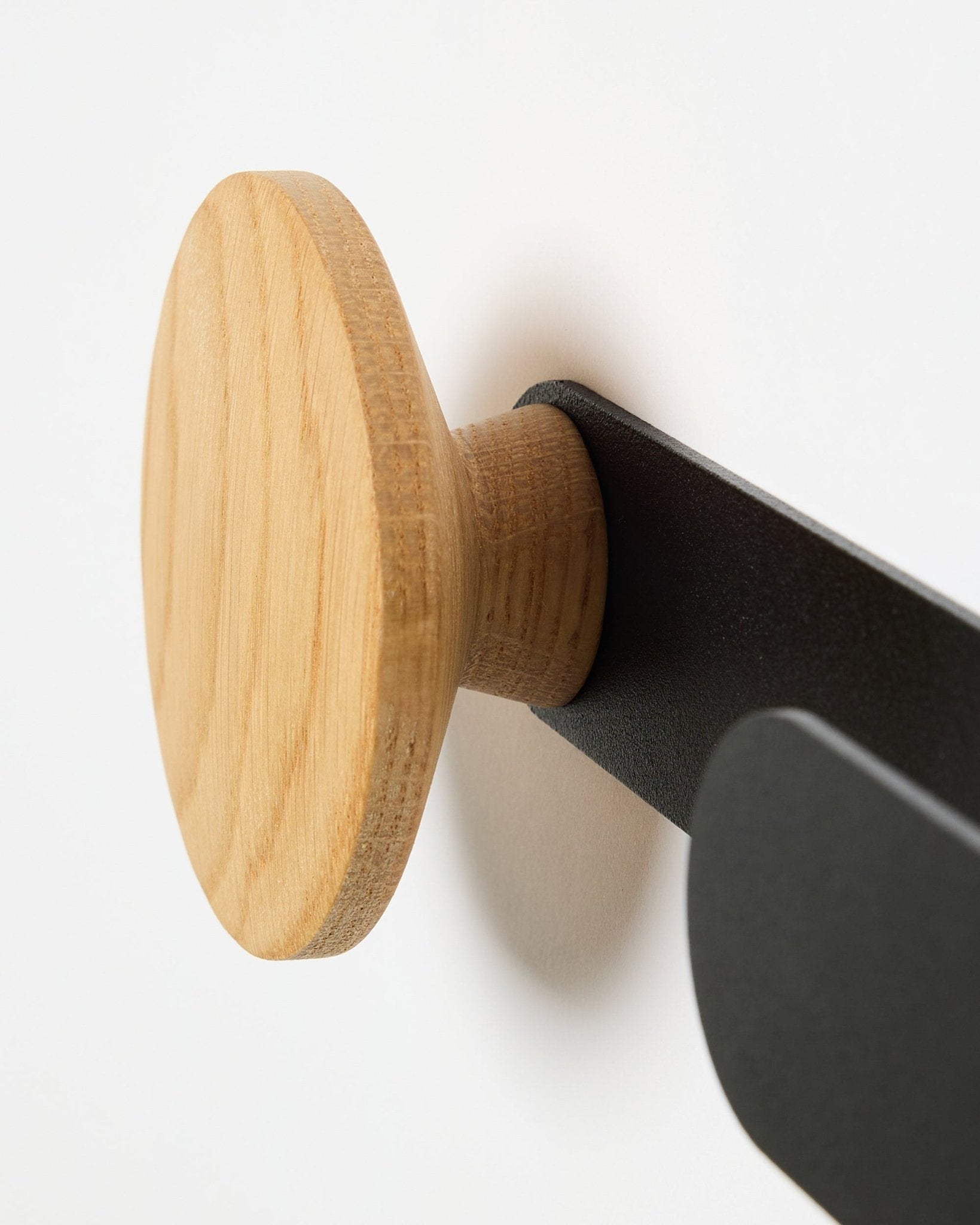 Close-up of WoodUpp Linn Horizontal Hanger in natural oak on a black metal bracket, designed for Akupanel acoustic panels or as a functional wall hook.