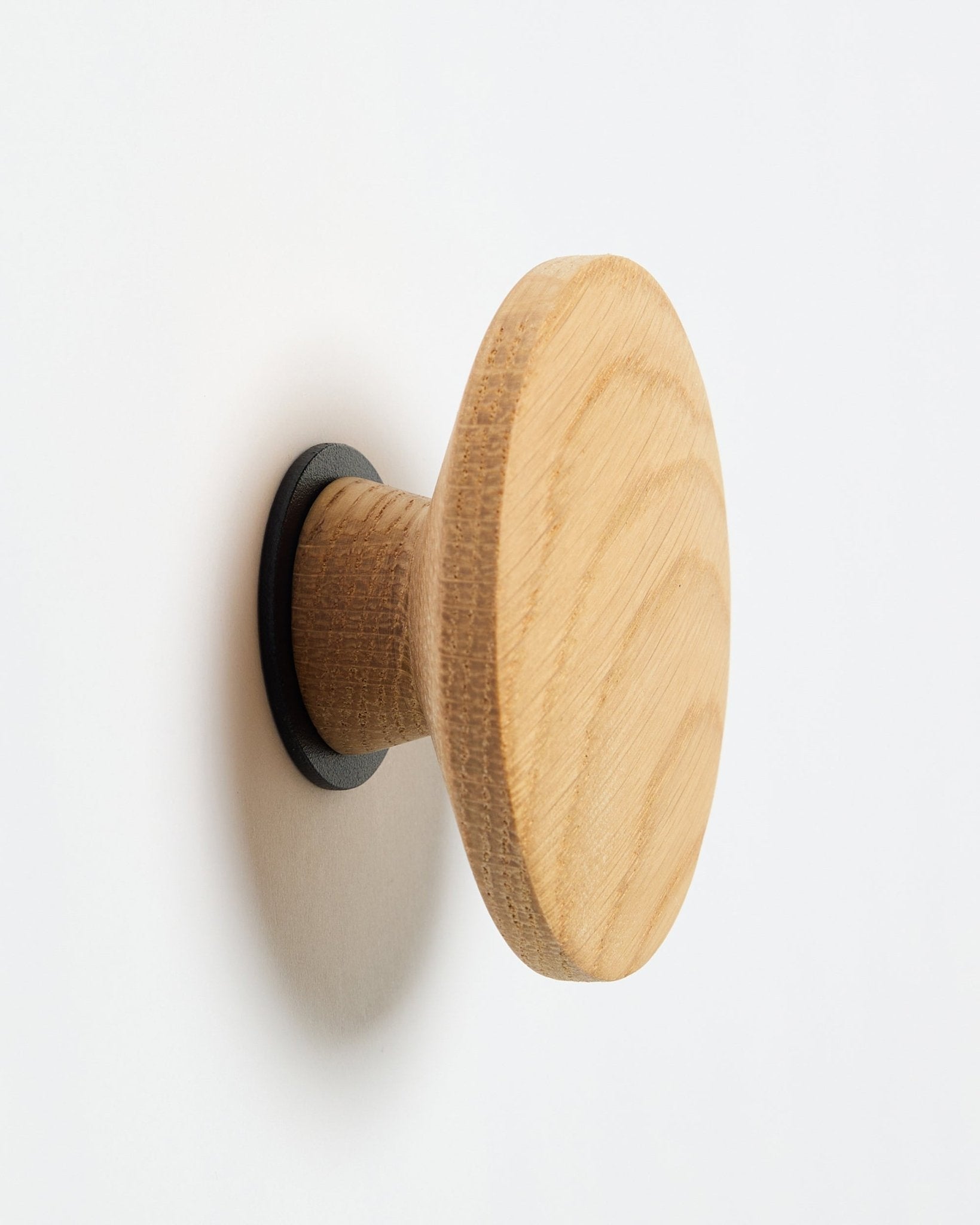 WoodUpp Linn I Single Hanger in natural oak, a round wall hook with black base, designed as an accessory for mounting on Akupanel acoustic wood panels.