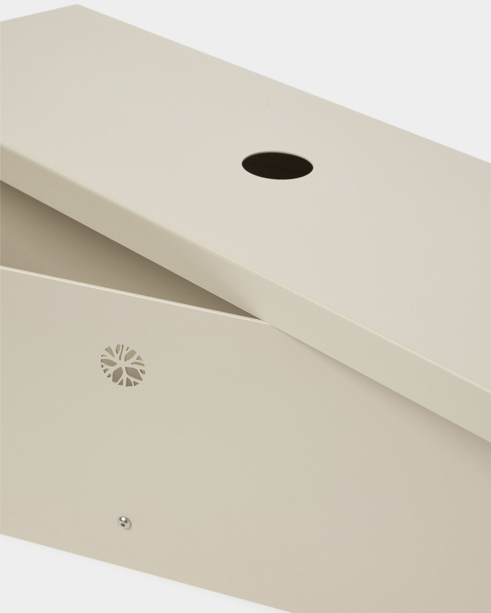 The Nell | Metal Box / BM2, Beige by WoodUpp crafted from powder-lacquered steel with a slanted lid, circular opening, and discreet side emblem.