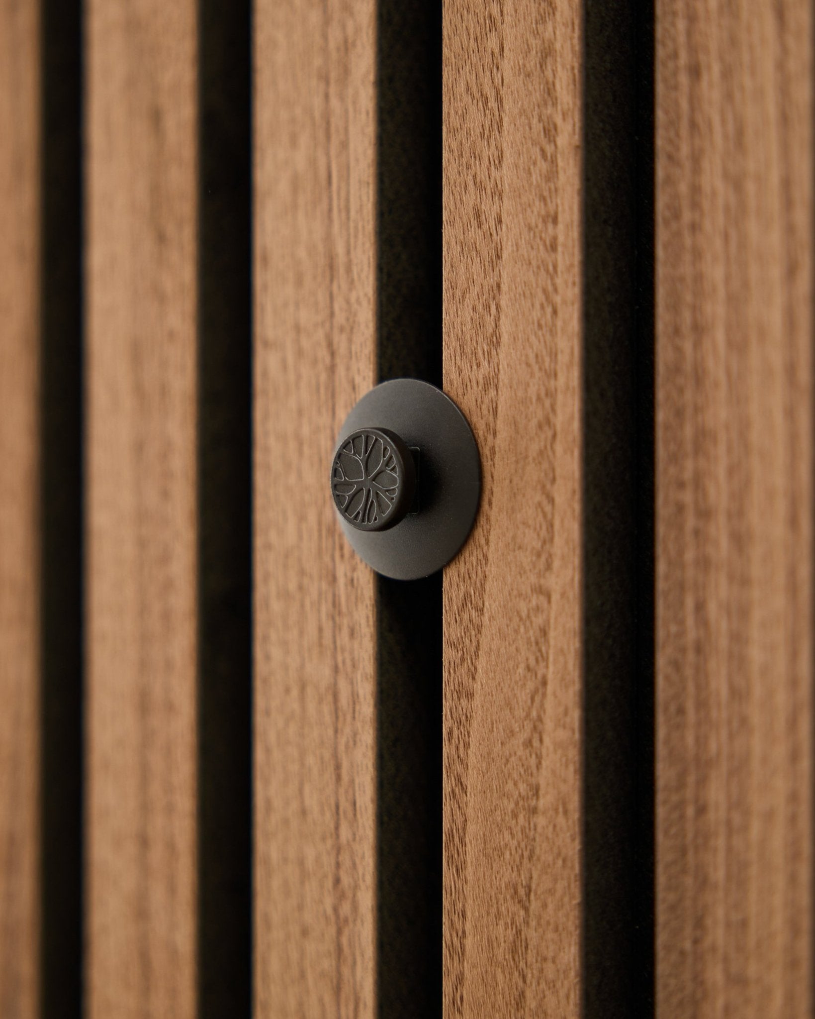 Close-up of a round black knob from the WoodUpp Dupps Original set, installed on a modern vertical Akupanel acoustic wood slat wall.