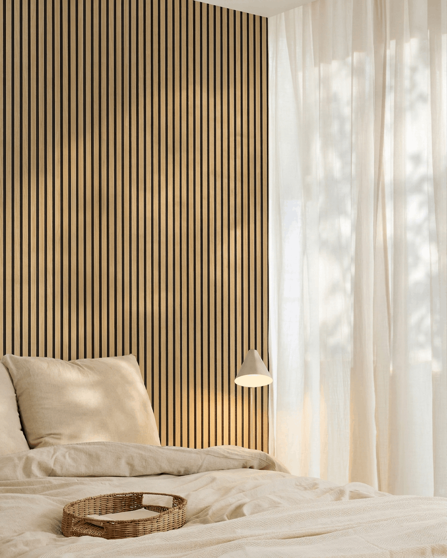 Minimalist bedroom featuring beige bedding, a WoodUpp Akupanel Southern Oak acoustic panel accent wall, woven tray on the bed, and sheer curtains allowing in natural light.