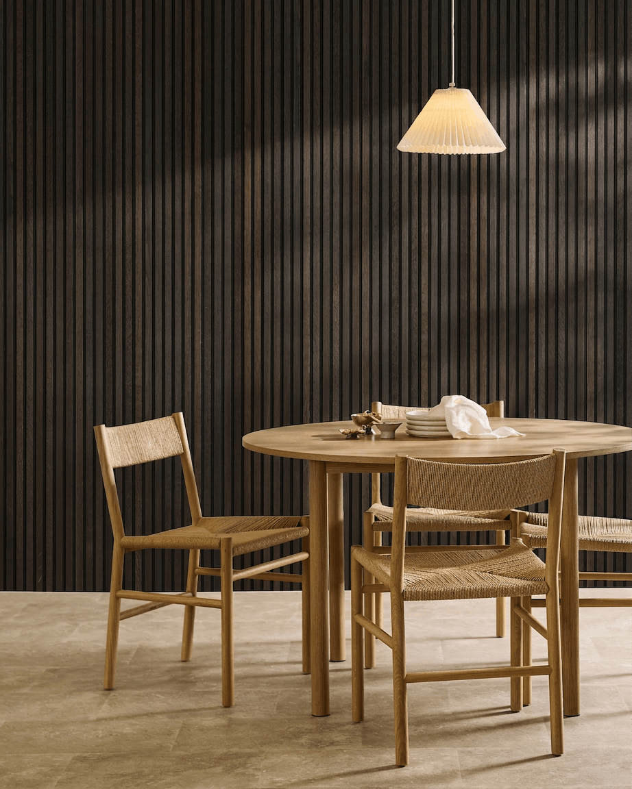 Minimalist dining area featuring a wooden table, Scandinavian chairs, pendant lamp, and a WoodUpp Akupanel Rustic Smoked Oak acoustic slatwall panel.