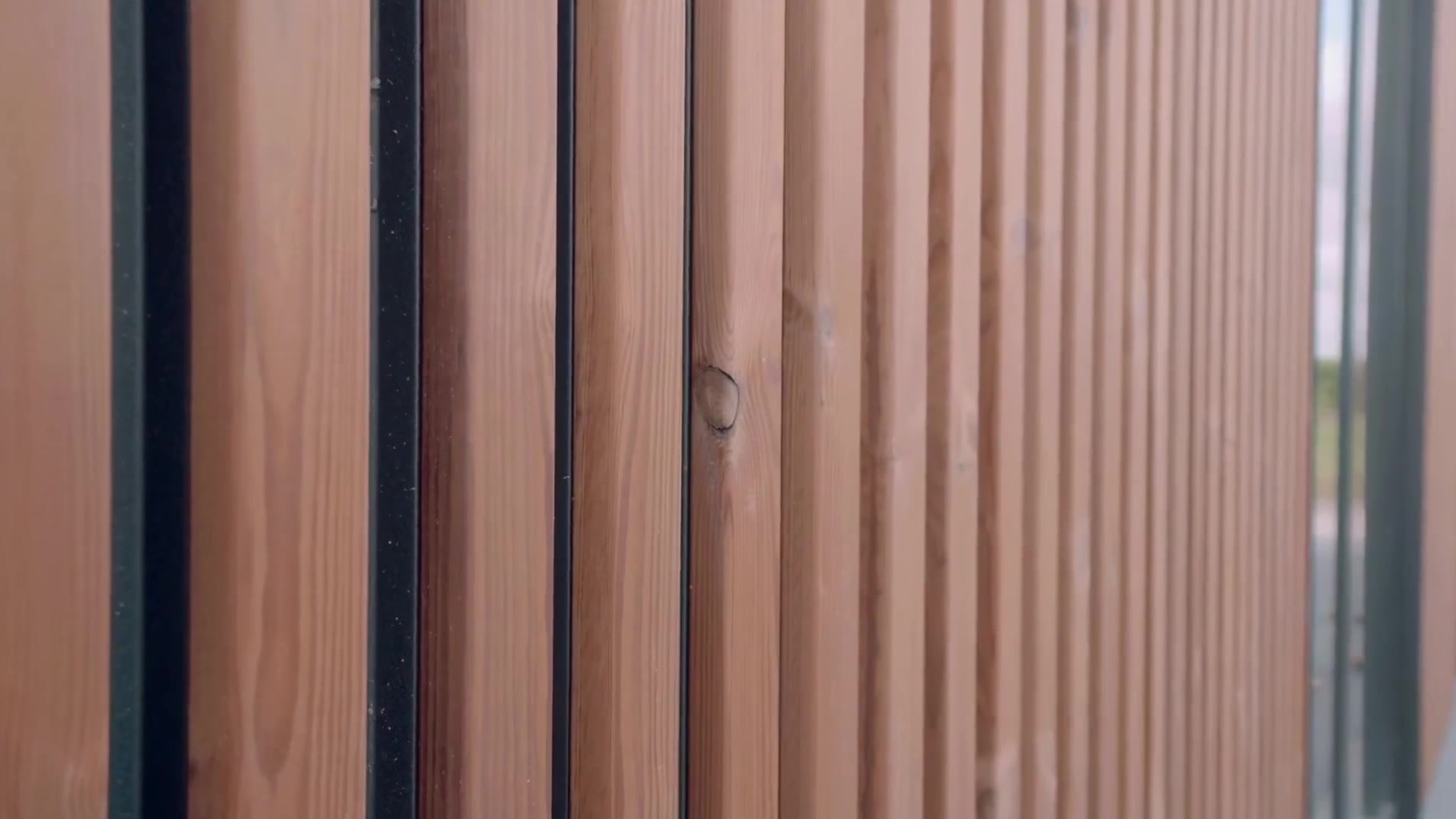 Close-up of vertical Aluwood slats showing wood grain, a knot and dark gaps between the slats