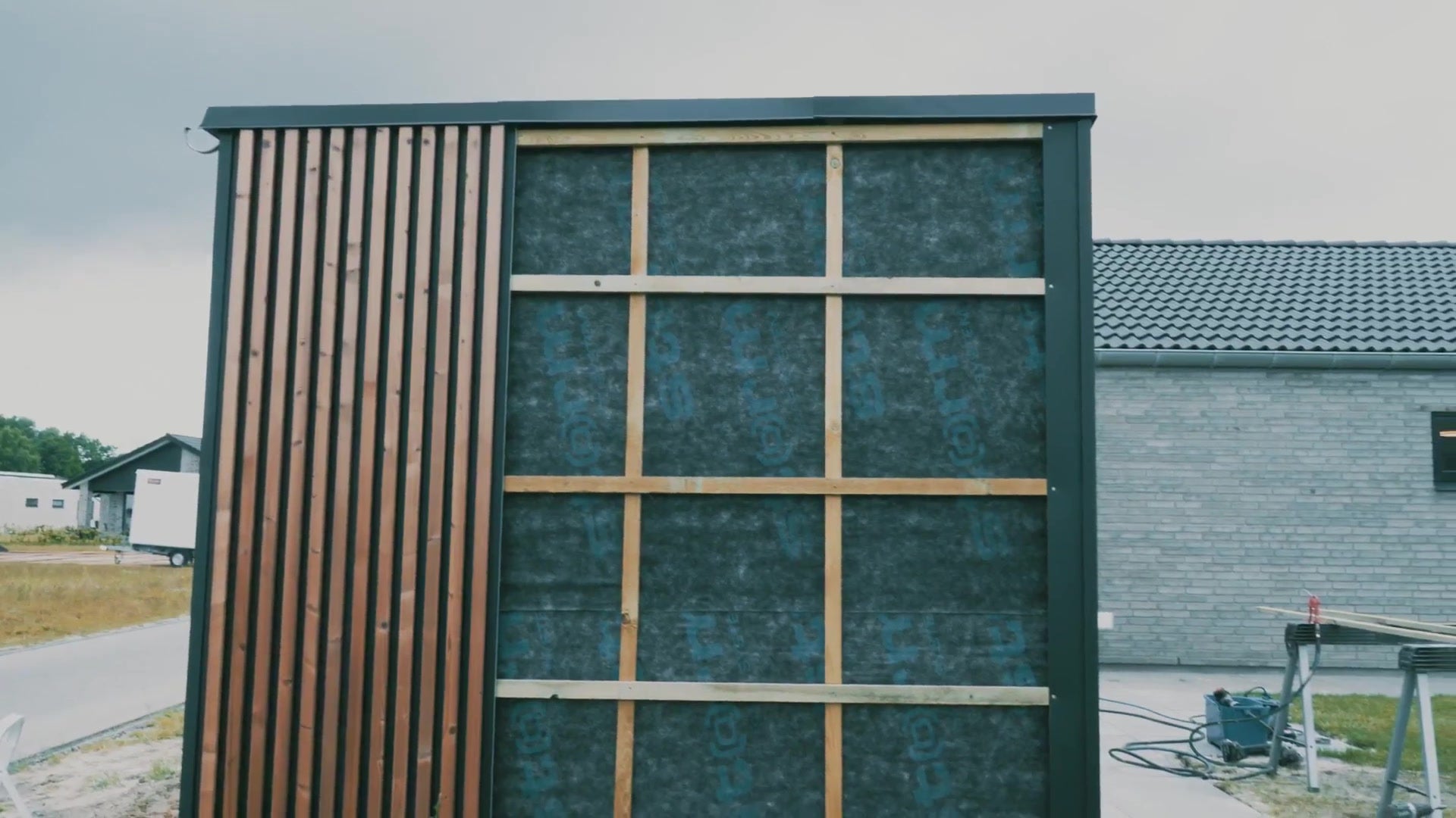 Garden shed with Aluwood slats fixed on one side and the membrane and battens still visible on the rest